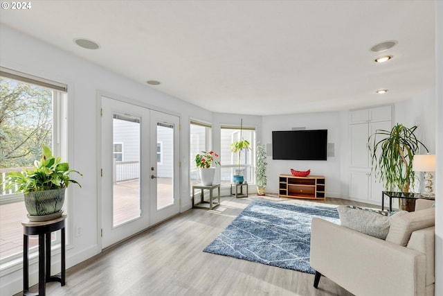 living area featuring light wood-type flooring, a wealth of natural light, and french doors