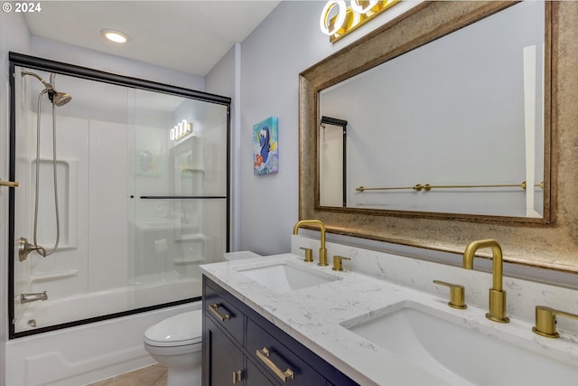 bathroom featuring bath / shower combo with glass door, double vanity, a sink, and toilet