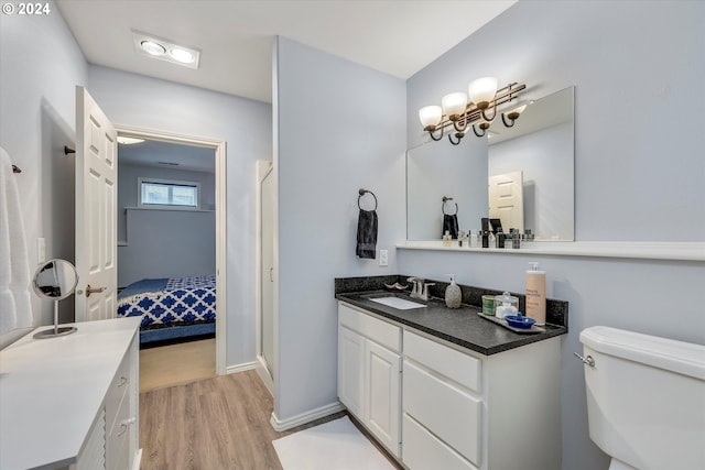 ensuite bathroom featuring baseboards, connected bathroom, toilet, wood finished floors, and vanity