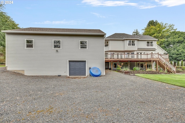 rear view of house with driveway, a garage, stairway, and a wooden deck