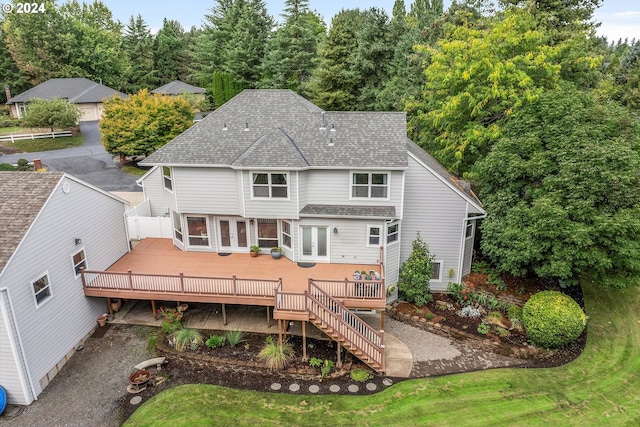 rear view of property featuring a shingled roof, stairway, and a deck