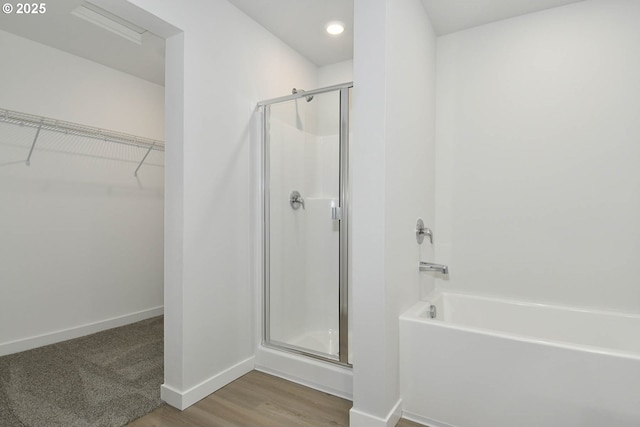 bathroom with hardwood / wood-style flooring and shower with separate bathtub