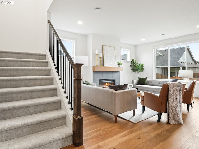 living room with a tiled fireplace and wood-type flooring