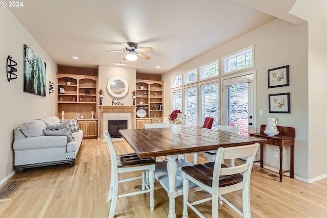 dining space with built in shelves, ceiling fan, and light hardwood / wood-style floors