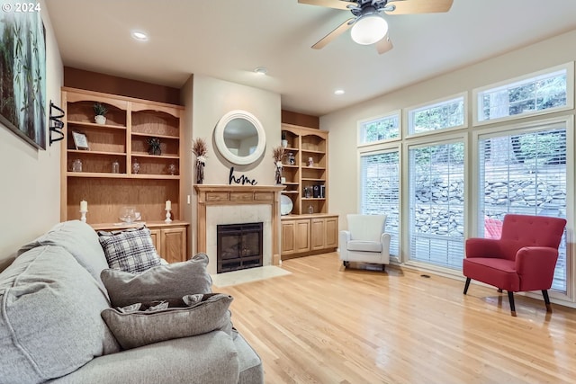 living area featuring ceiling fan, a fireplace, and light wood-type flooring