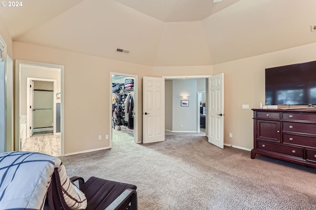 bedroom with light carpet, a walk in closet, a closet, and vaulted ceiling