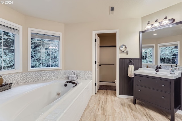 bathroom with vanity and tiled bath