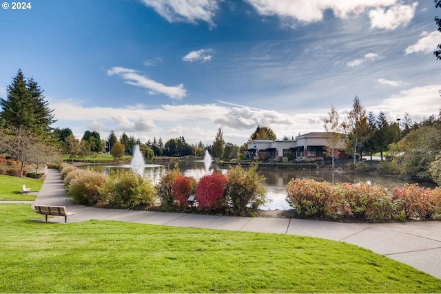 surrounding community with a water view and a lawn