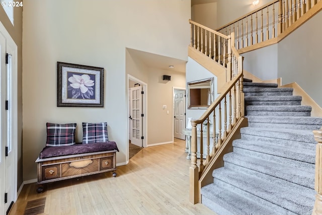 stairway featuring a towering ceiling and hardwood / wood-style floors