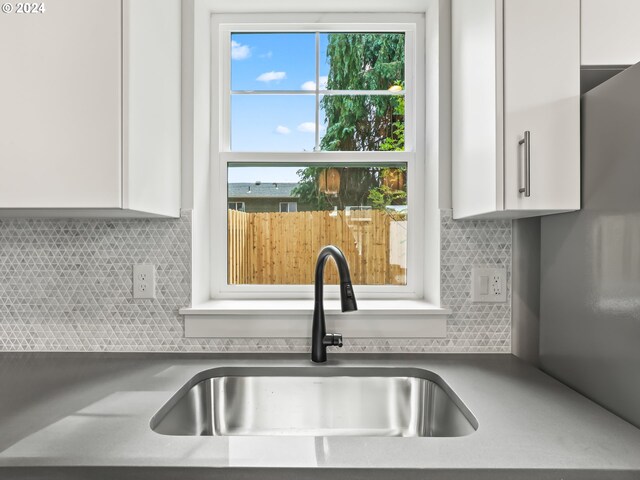 room details featuring white cabinetry, sink, and tasteful backsplash