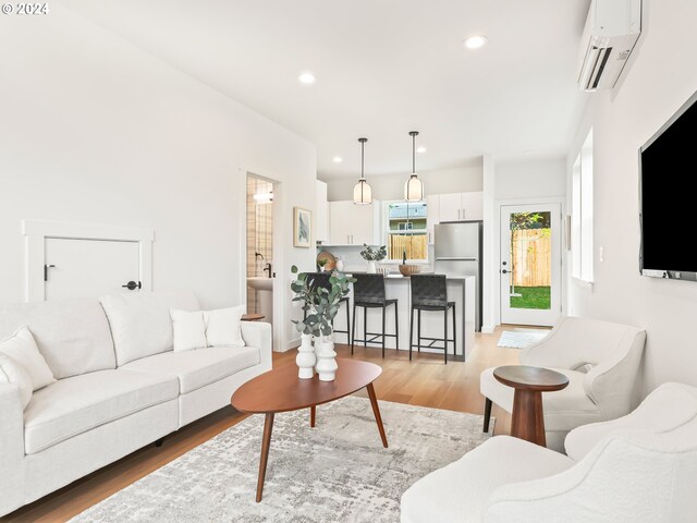 living room featuring a wall mounted AC and light hardwood / wood-style flooring