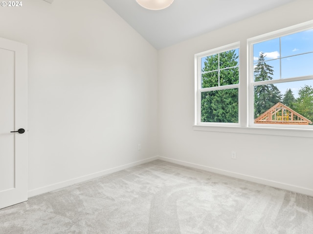 unfurnished room with lofted ceiling, light carpet, and baseboards