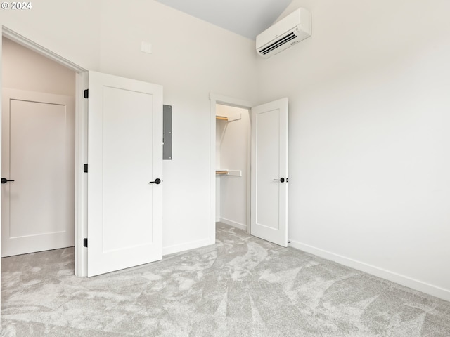 unfurnished bedroom featuring a closet, a spacious closet, an AC wall unit, and light colored carpet