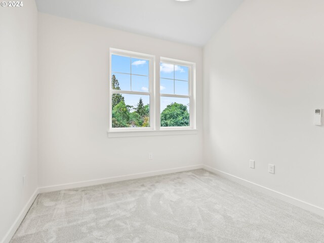 carpeted empty room featuring lofted ceiling