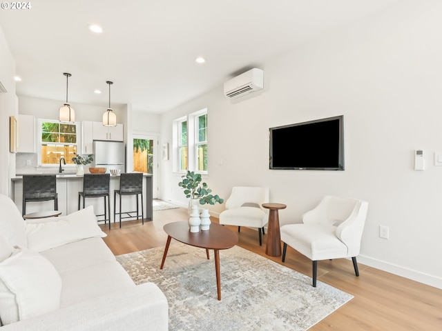 living area featuring a healthy amount of sunlight, light wood-style flooring, and a wall mounted AC