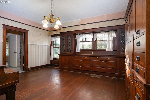 dining area featuring dark wood-type flooring, a textured ceiling, wooden walls, and an inviting chandelier