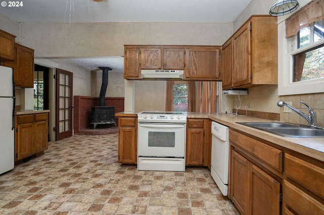 kitchen featuring white appliances, sink, a wood stove, and kitchen peninsula