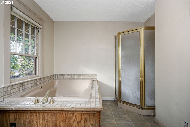 bathroom with a textured ceiling, tile patterned flooring, and separate shower and tub