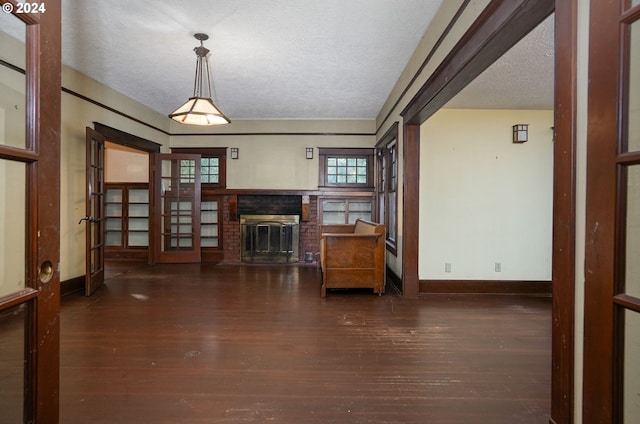 unfurnished living room with a brick fireplace, dark wood-type flooring, and a textured ceiling