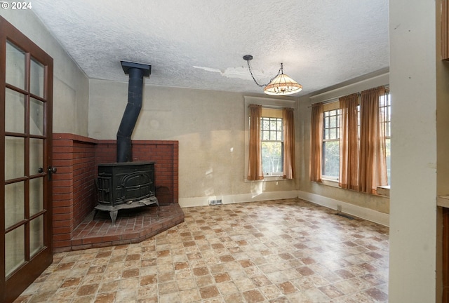 unfurnished living room with a wood stove and a textured ceiling