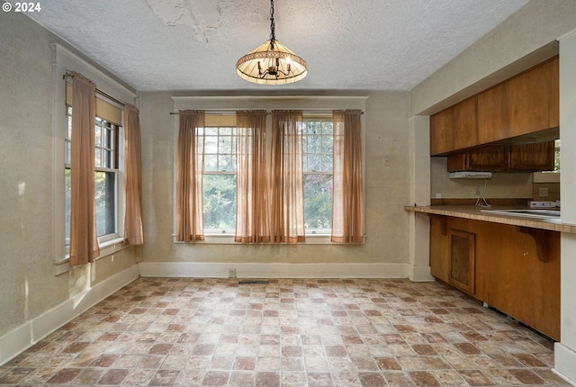 unfurnished dining area featuring a textured ceiling and a notable chandelier