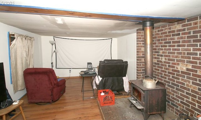 interior space with a wood stove, hardwood / wood-style floors, and brick wall