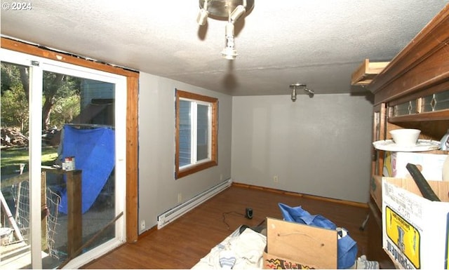 interior space featuring wood finished floors, baseboards, a textured ceiling, and a baseboard heating unit