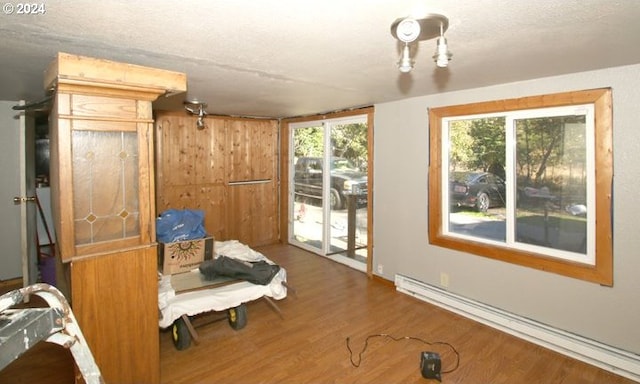 sitting room with hardwood / wood-style flooring, a textured ceiling, a baseboard heating unit, and wood walls