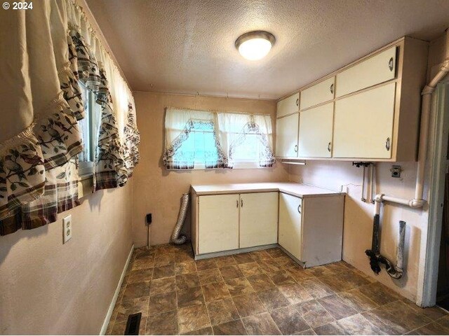 kitchen featuring dark tile patterned flooring, a textured ceiling, and cream cabinets