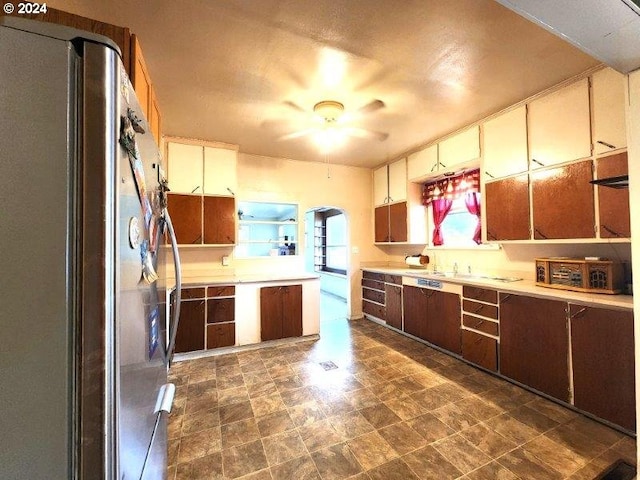 kitchen featuring arched walkways, light countertops, and freestanding refrigerator