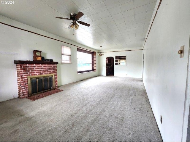 unfurnished living room with carpet, a fireplace, and a ceiling fan