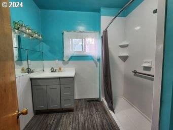 full bathroom featuring a stall shower, wood finished floors, and vanity