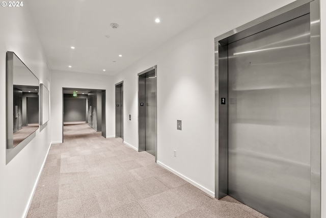 hall featuring light colored carpet and elevator