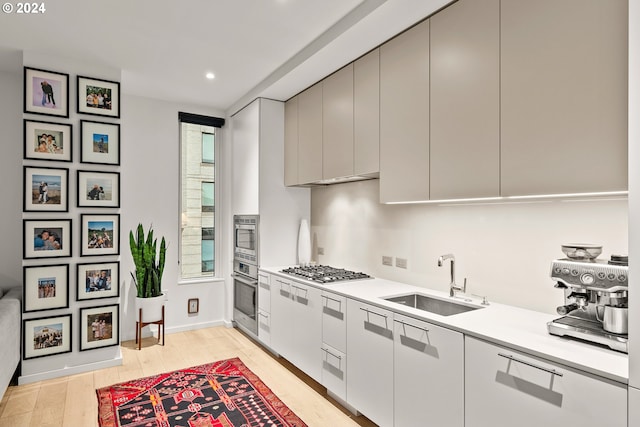 kitchen with stainless steel appliances, sink, and light hardwood / wood-style floors