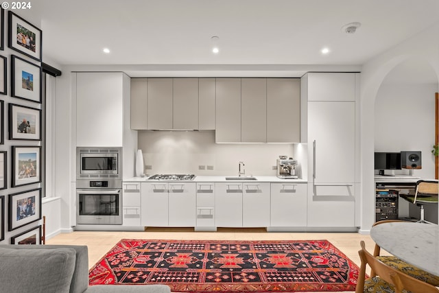 kitchen featuring gray cabinetry, stainless steel appliances, light hardwood / wood-style floors, and sink