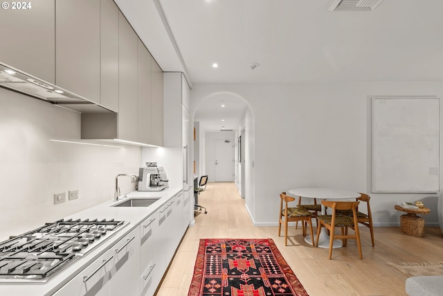 kitchen with stainless steel gas cooktop, light hardwood / wood-style flooring, and sink