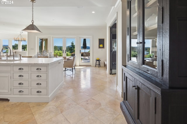 interior space featuring white cabinetry, hanging light fixtures, a healthy amount of sunlight, and sink