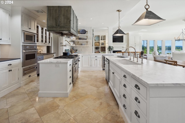 kitchen with appliances with stainless steel finishes, backsplash, decorative light fixtures, a center island with sink, and sink