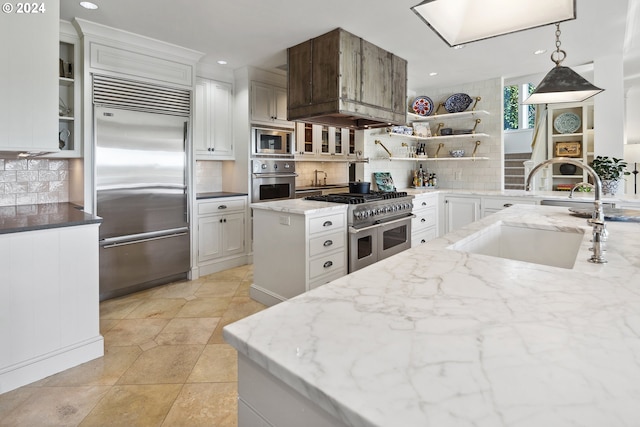 kitchen with decorative backsplash, white cabinetry, built in appliances, pendant lighting, and sink