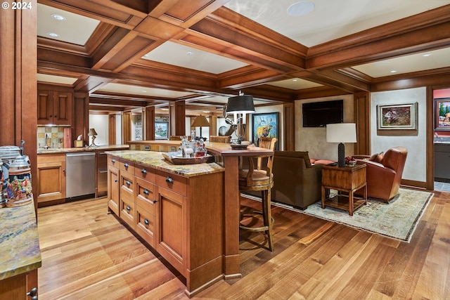 kitchen with light stone counters, light wood-type flooring, a kitchen bar, decorative light fixtures, and stainless steel dishwasher