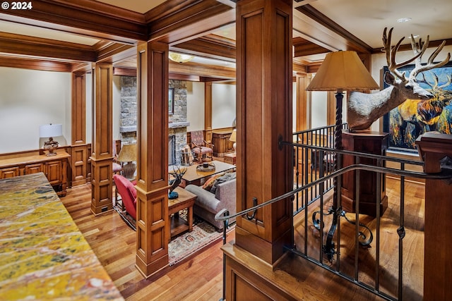 interior space featuring decorative columns, crown molding, light hardwood / wood-style floors, and beamed ceiling