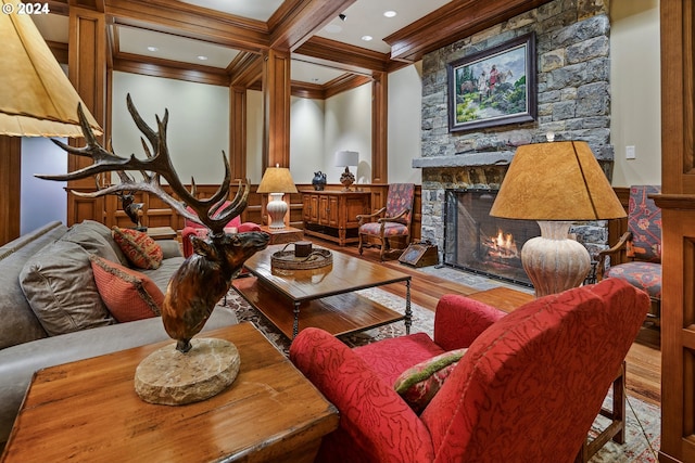 living room featuring ornamental molding, a stone fireplace, beam ceiling, and hardwood / wood-style flooring