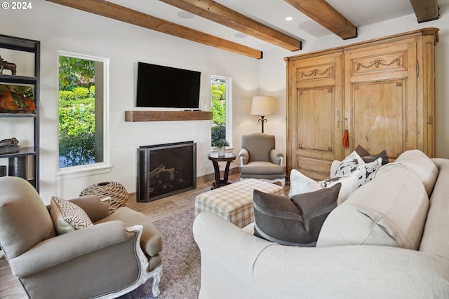 living room featuring beamed ceiling, light hardwood / wood-style flooring, and a wealth of natural light