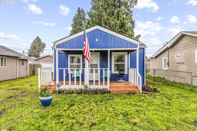 rear view of house featuring a porch and a lawn