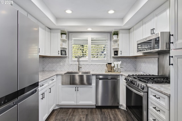 kitchen with stainless steel appliances, sink, white cabinets, and light stone counters