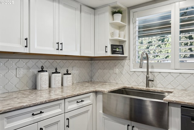 kitchen featuring light stone counters, backsplash, sink, and white cabinets