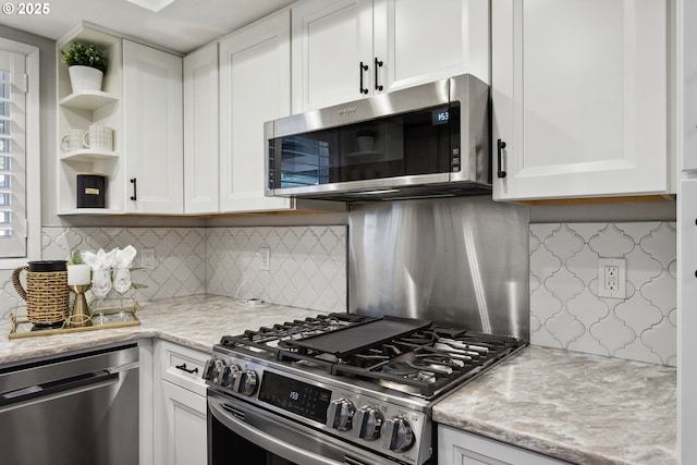 kitchen featuring backsplash, light stone countertops, white cabinets, and appliances with stainless steel finishes