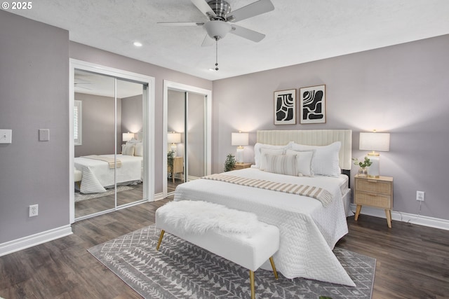 bedroom featuring multiple closets, dark hardwood / wood-style floors, a textured ceiling, and ceiling fan