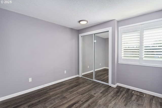 unfurnished bedroom featuring a closet, dark hardwood / wood-style floors, and a textured ceiling