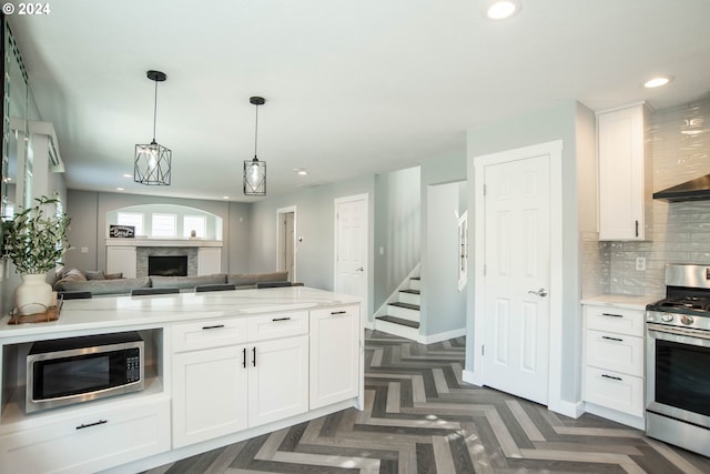 kitchen with light stone counters, dark parquet floors, white cabinets, and appliances with stainless steel finishes